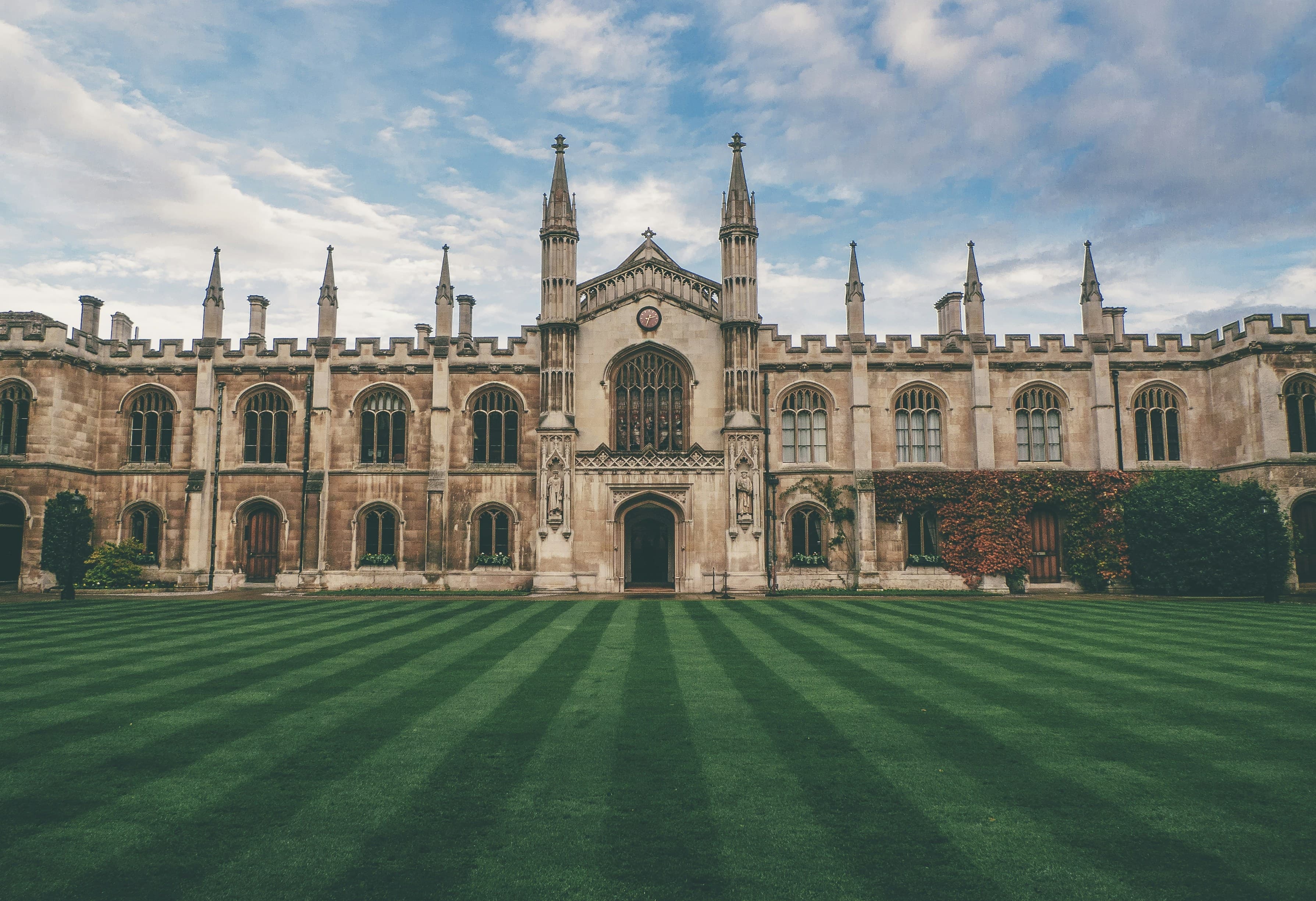 A historic college building behind a striped green lawn